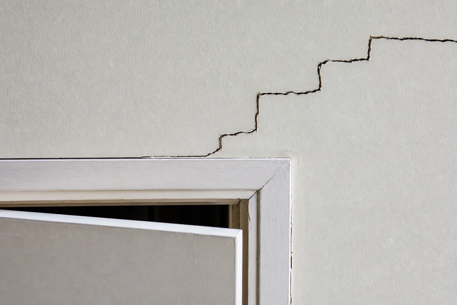 Fissure oblique en escalier au-dessus d'une ouverture, contrôle structurel lors d'une expertise avant achat